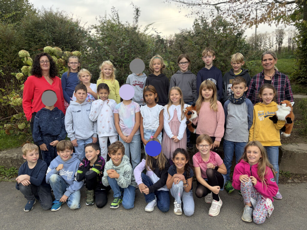 Die Klasse 3B mit ihren Lehrerinnen vor der Hecke